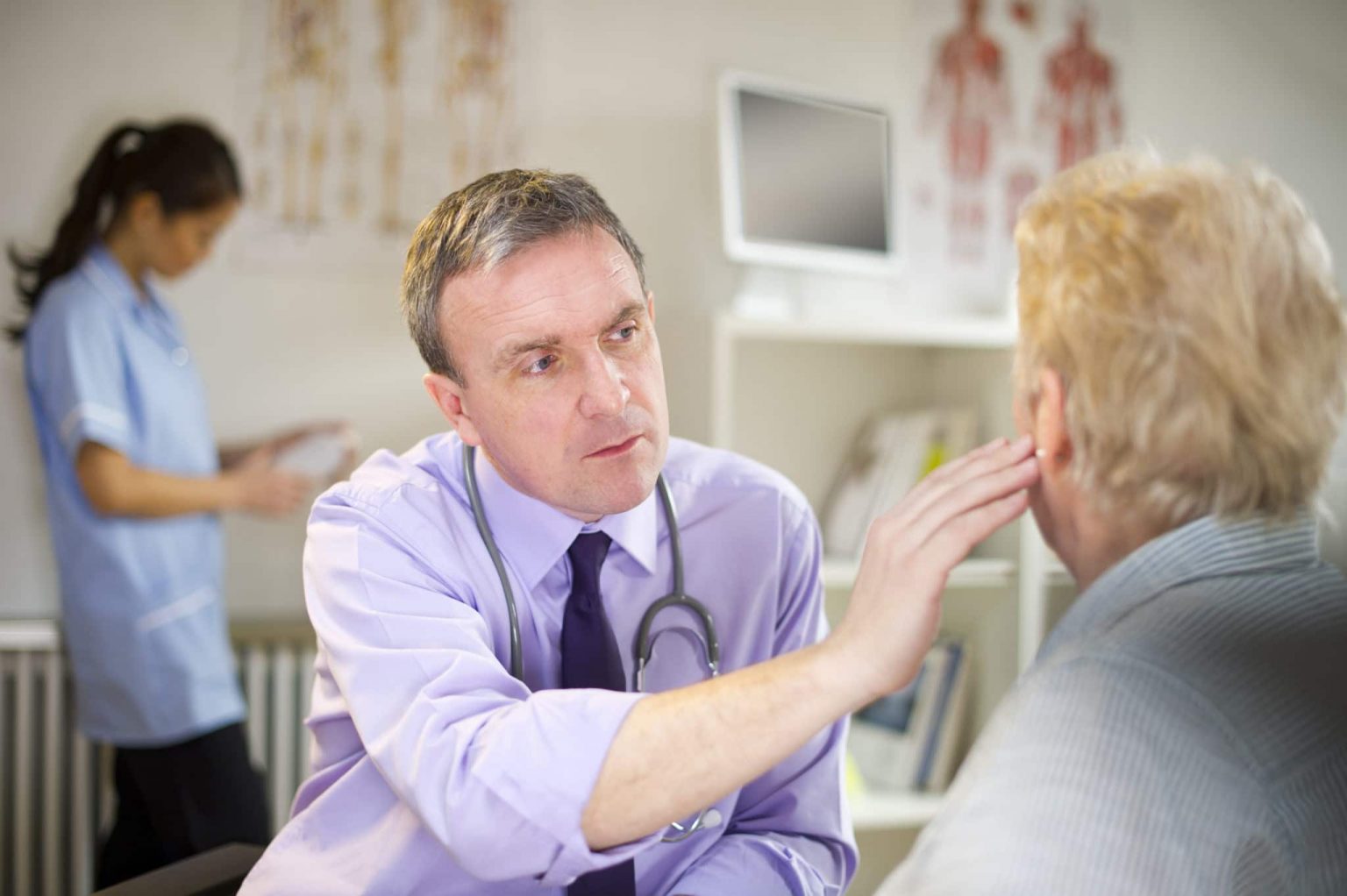 ENT inspecting an older patients ears for indications of an earwax blockage