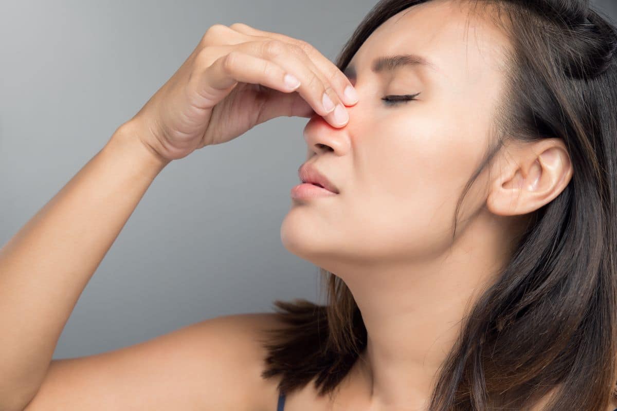 woman in need of sinusitis diagnosis Woman holding the bridge of her nose due to pain caused by sinusitis